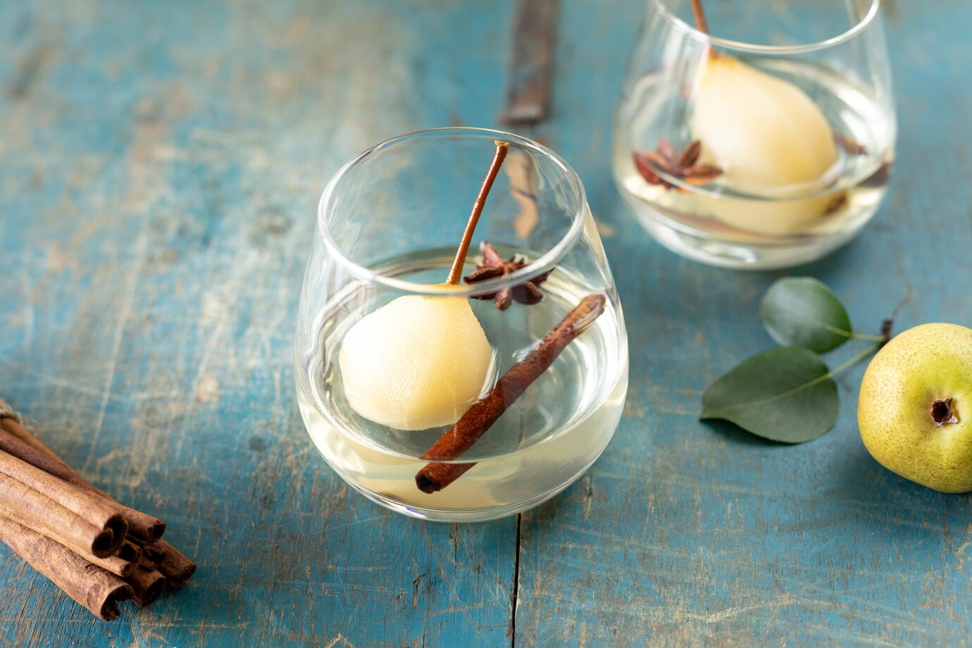 dos-vasos-bebida-peras-dulces-guisadas-vino-blanco-sobre-mesa-madera-postre-festivo_127032-2539